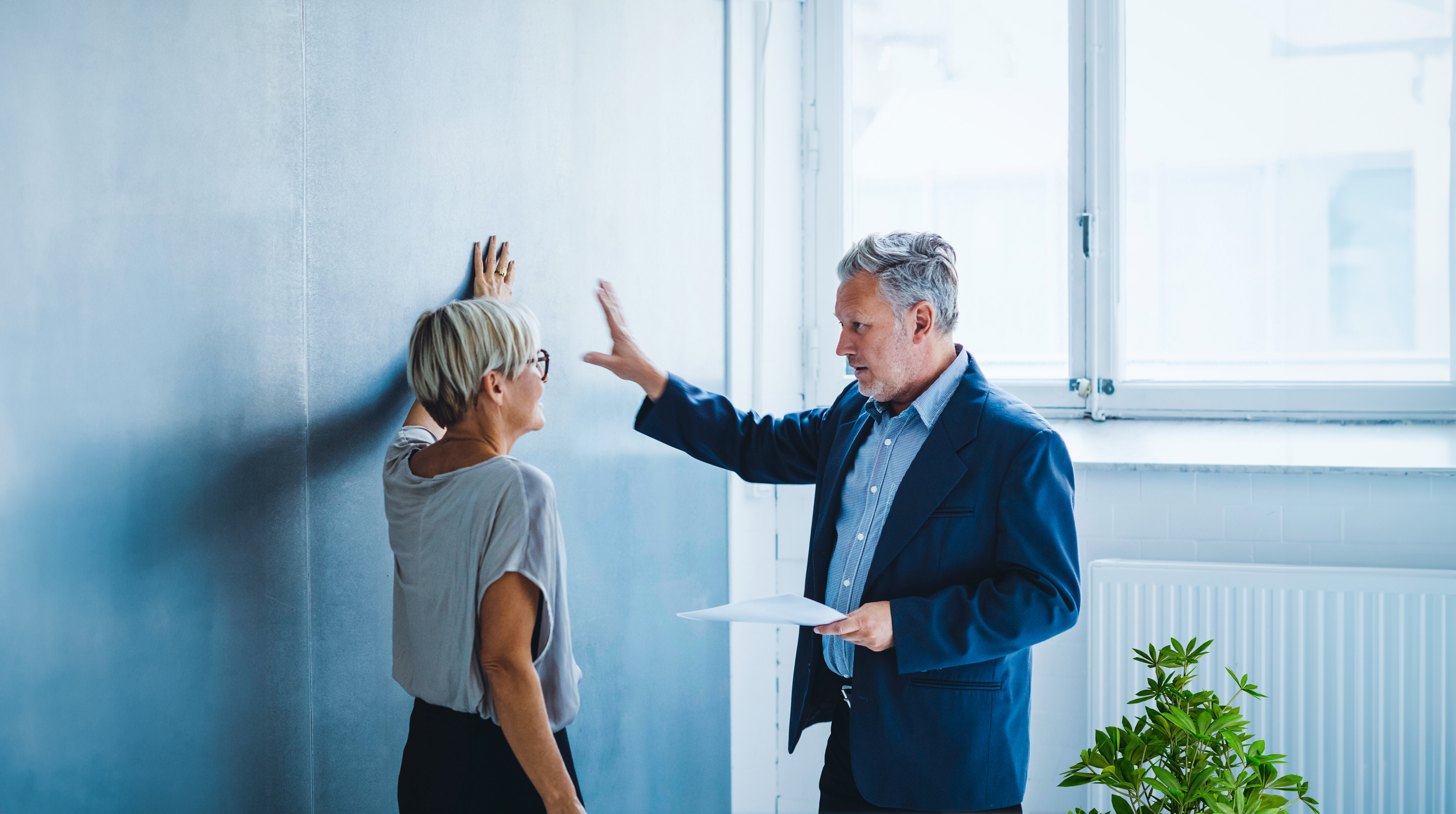 Ein Mann und eine Frau lehnen gegen eine Wand und unterhalten sich angeregt 