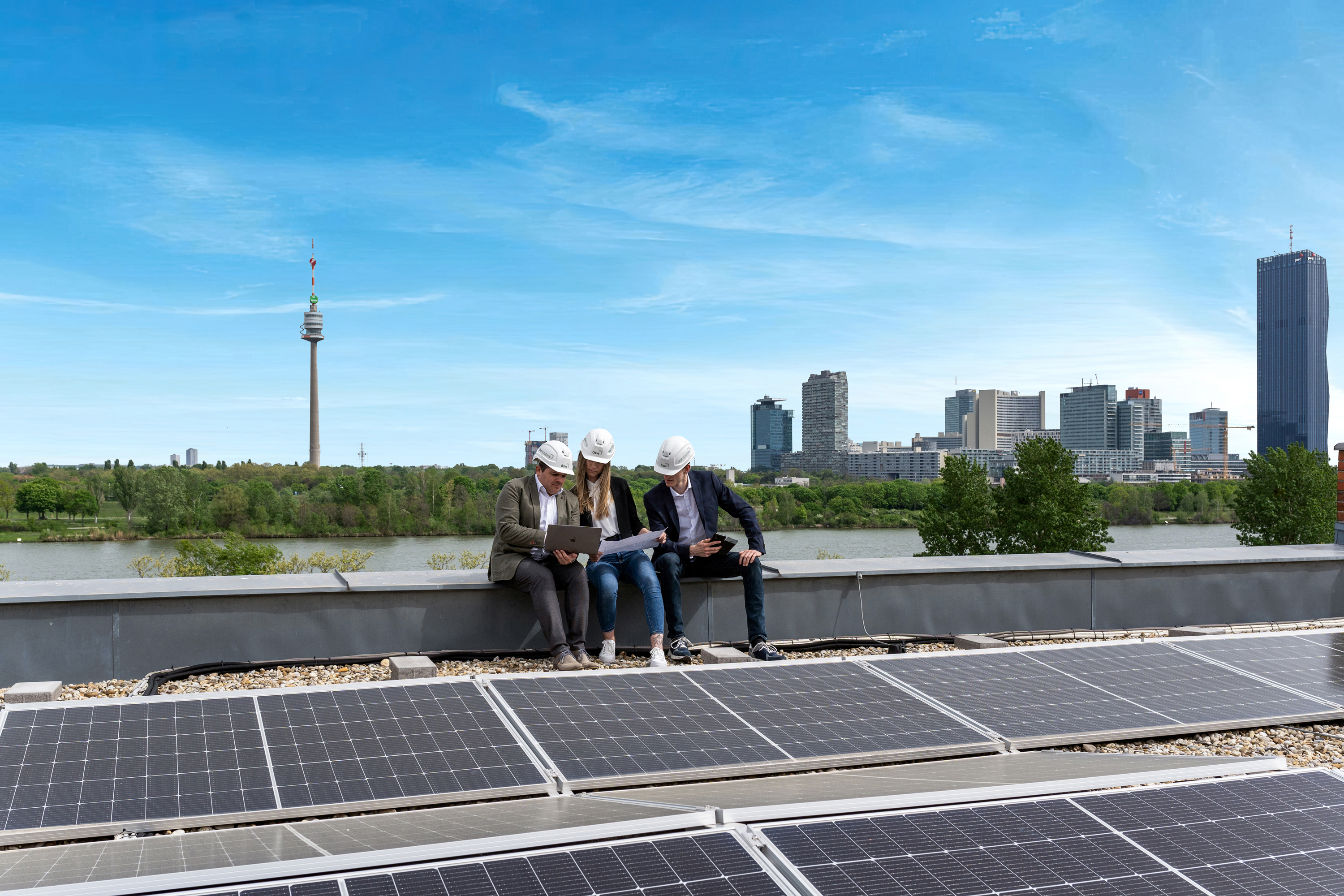 Drei ÖSW Mitarbeiter begutachten konzentriert die Photovoltaik-Anlage am Dach der Zweigstellle am Handelskai