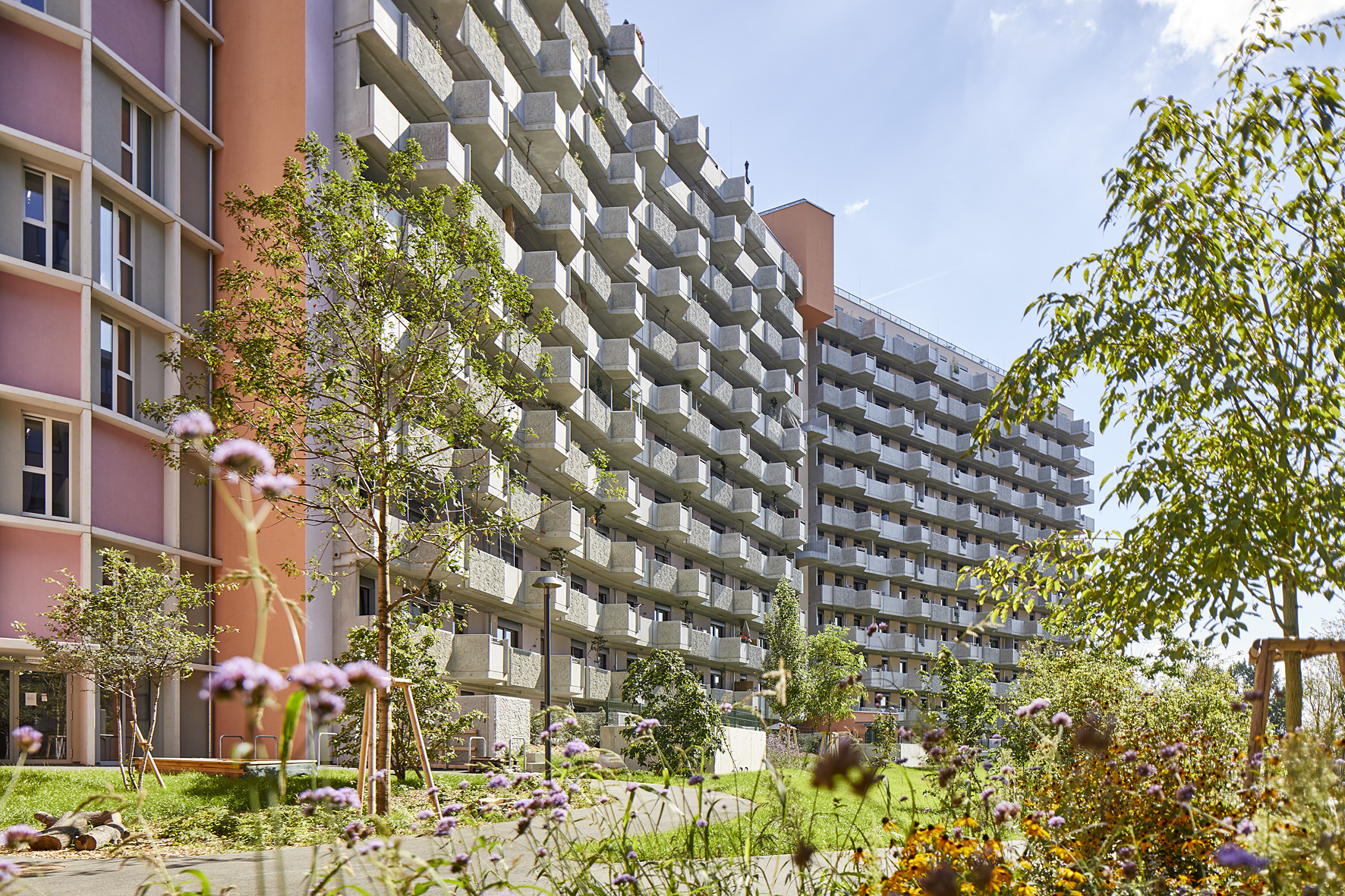 Außenansicht der Biotope City mit angrenzendem Grünraum bei Sonnenschein am Wienerberg in 1100 Wien